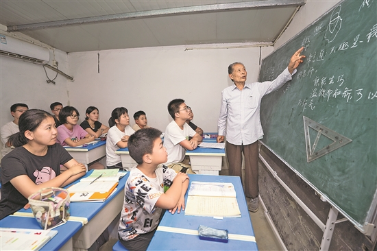 粉笔,在黑板上边画图边讲解几何题,讲台下十余名学生做着笔记